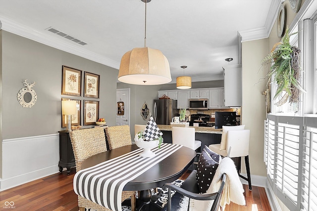dining area with dark wood-style floors, crown molding, and baseboards