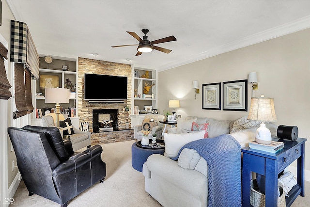 carpeted living room with a ceiling fan, crown molding, a fireplace, built in shelves, and baseboards
