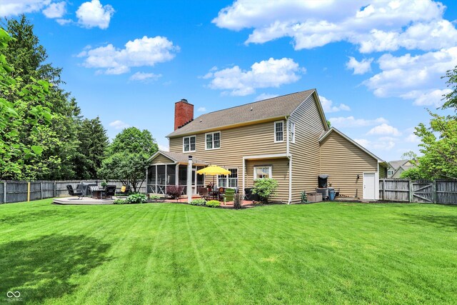 rear view of property with a sunroom, a chimney, a patio, and a deck