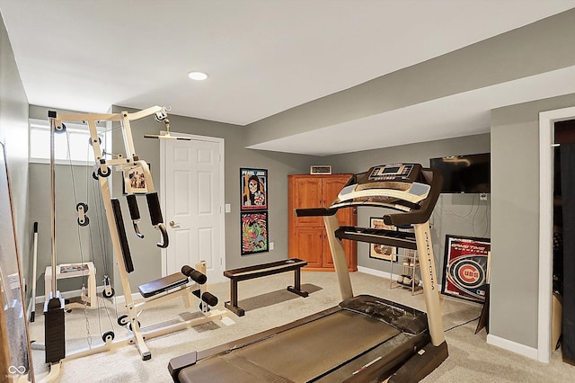 exercise room featuring baseboards and light carpet