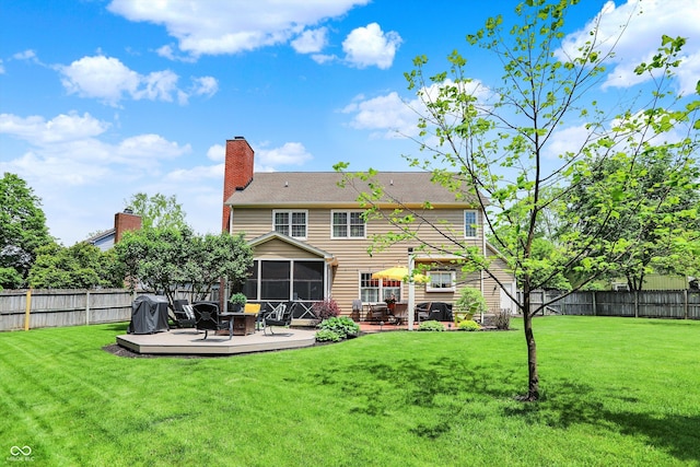 rear view of house featuring a sunroom, a wooden deck, a chimney, and a patio