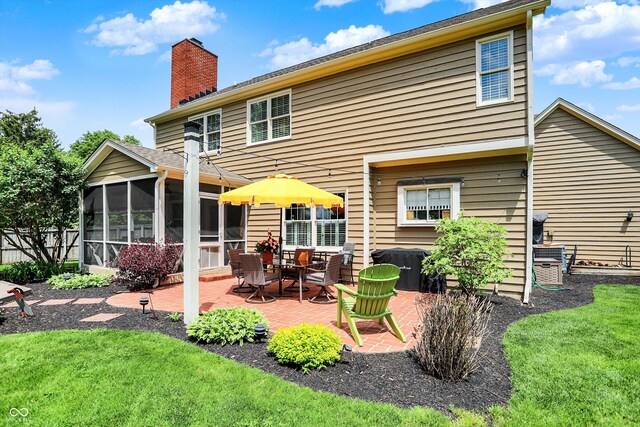 back of property with a patio area, a sunroom, and a chimney