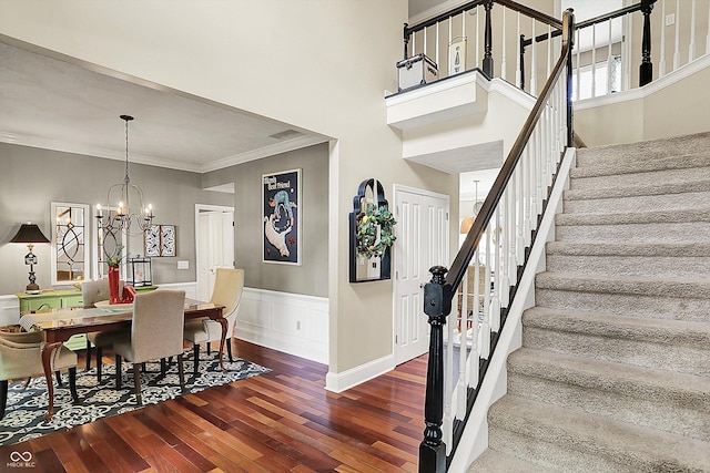 dining room with hardwood / wood-style floors, stairway, crown molding, a wainscoted wall, and a chandelier