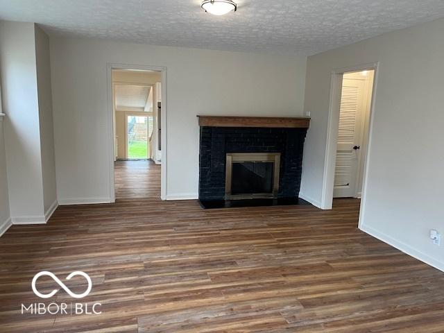 223 E Fordice St, Lebanon, IN 46052 - unfurnished living room featuring baseboards, a textured ceiling, wood finished floors, and a fireplace