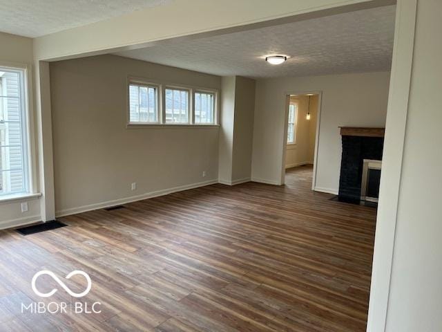 223 E Fordice St, Lebanon, IN 46052 - unfurnished living room with a textured ceiling, a fireplace with flush hearth, baseboards, and wood finished floors