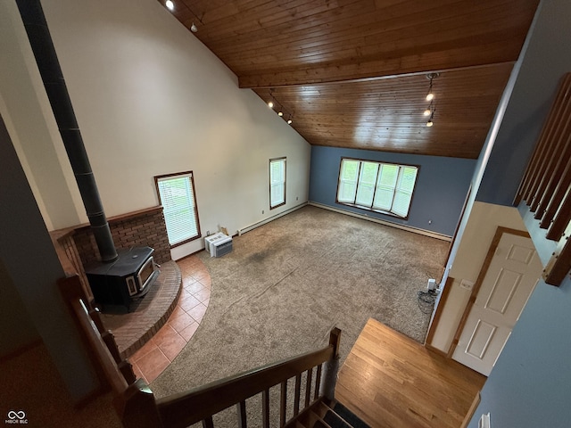 7140 N Michigan Rd, Fairland, IN 46126 - unfurnished living room featuring rail lighting, wooden ceiling, plenty of natural light, a wood stove, and baseboards
