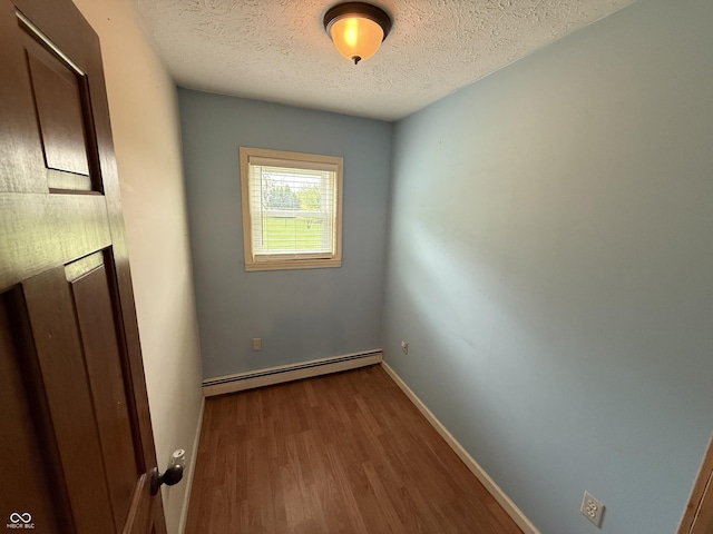 7140 N Michigan Rd, Fairland, IN 46126 - empty room with a baseboard heating unit, a textured ceiling, wood finished floors, and baseboards