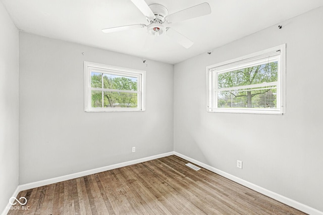 empty room with ceiling fan, baseboards, visible vents, and wood finished floors