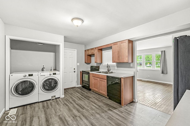 washroom with washer and dryer, wood finished floors, baseboards, and a sink