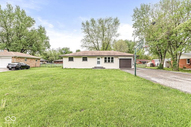 ranch-style home featuring driveway, a front yard, an attached garage, and fence
