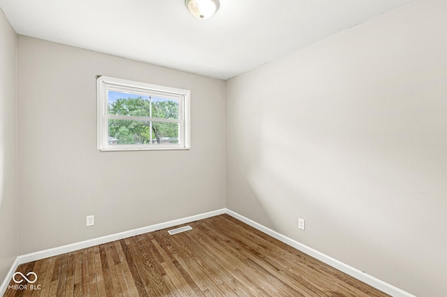 unfurnished room featuring baseboards, visible vents, and wood finished floors
