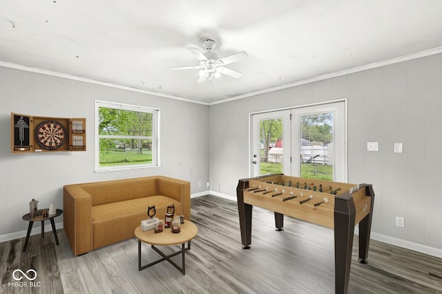 game room with baseboards, a wealth of natural light, ornamental molding, and wood finished floors