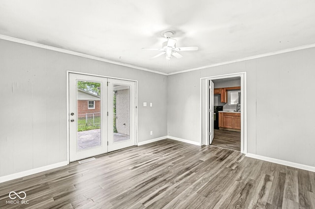 empty room featuring baseboards, ceiling fan, crown molding, and wood finished floors