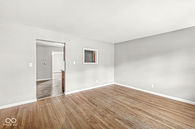 spare room featuring baseboards and wood finished floors