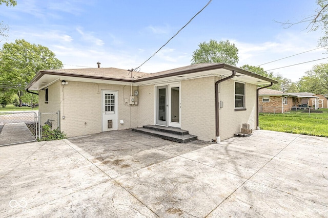 back of house featuring brick siding, fence, and a patio area