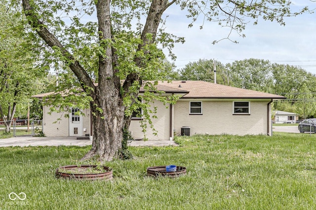 exterior space with a yard, cooling unit, brick siding, and fence