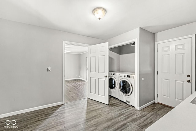 washroom featuring washing machine and clothes dryer, laundry area, baseboards, and wood finished floors
