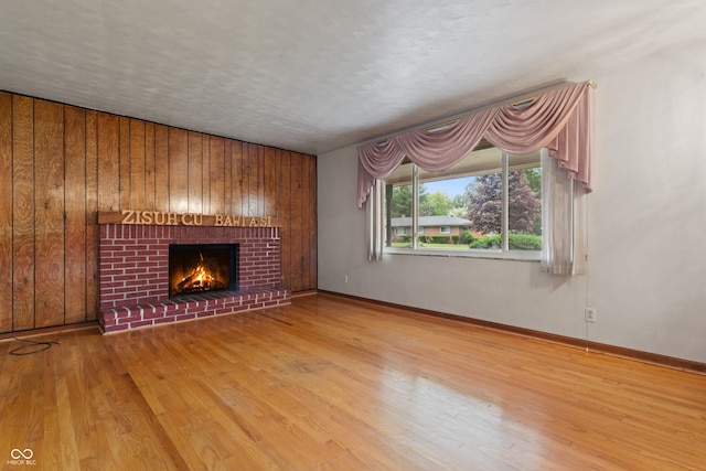 unfurnished living room featuring baseboards, a brick fireplace, wood finished floors, and wooden walls