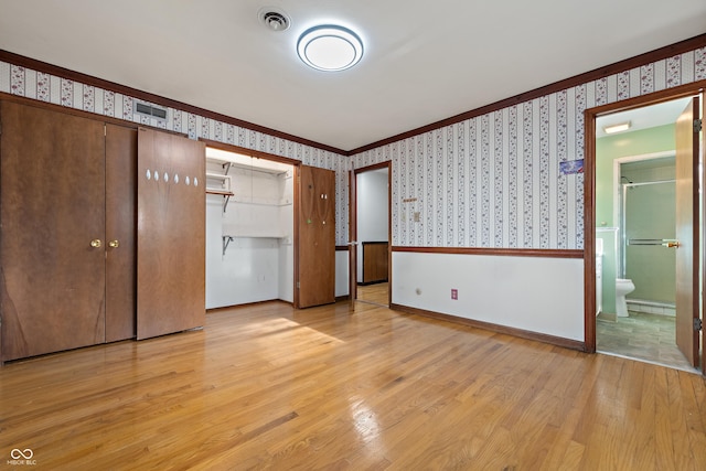 unfurnished bedroom with baseboards, a closet, light wood-style floors, ornamental molding, and wallpapered walls
