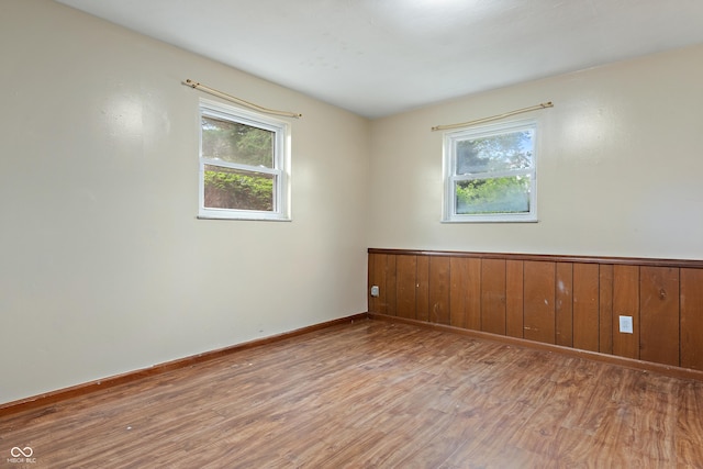spare room with baseboards, wainscoting, and light wood-type flooring