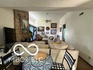living room with a textured ceiling, visible vents, and ceiling fan