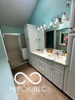 bathroom with double vanity, a stall shower, and a sink