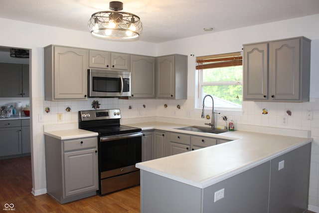8551 Walden Trace Dr, Indianapolis, IN 46278 - kitchen with appliances with stainless steel finishes, gray cabinetry, a sink, a peninsula, and wood finished floors