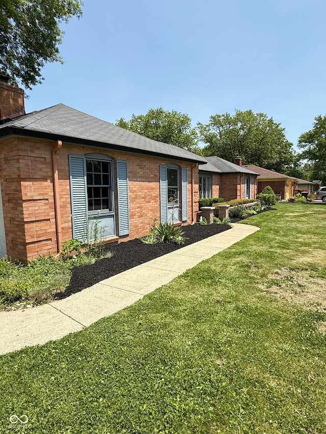 3128 W 12th St, Anderson, IN 46011 - view of front facade featuring brick siding, a front lawn, and a chimney