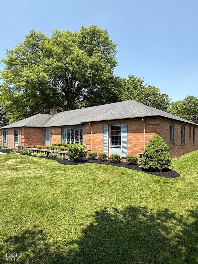 3128 W 12th St, Anderson, IN 46011 - ranch-style house featuring brick siding, a front yard, and a chimney