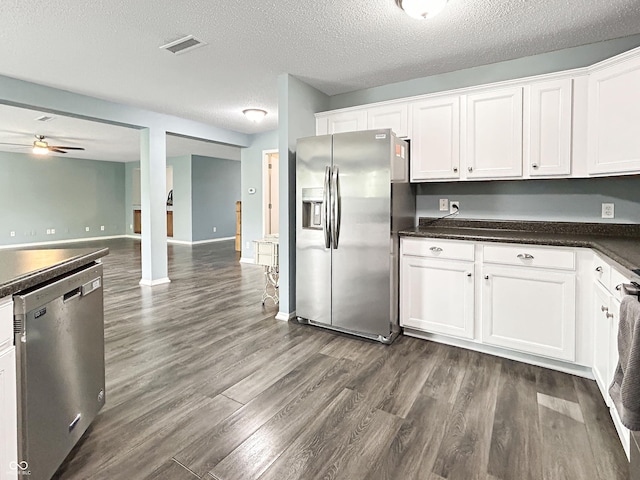 625 Streamside Dr, Greenfield, IN 46140 - kitchen with appliances with stainless steel finishes, dark countertops, dark wood-type flooring, white cabinets, and a textured ceiling