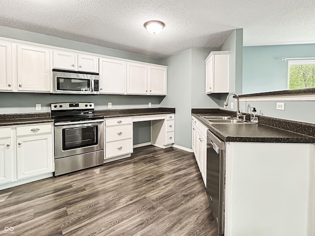 625 Streamside Dr, Greenfield, IN 46140 - kitchen featuring stainless steel appliances, a sink, a textured ceiling, white cabinets, and dark countertops