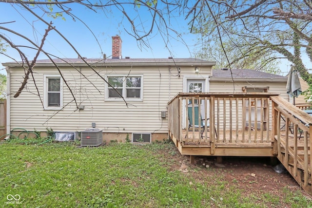 rear view of property with a chimney, cooling unit, a deck, and a lawn