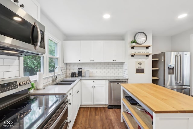 kitchen with butcher block counters, a sink, open shelves, decorative backsplash, and stainless steel appliances