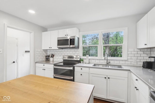 kitchen featuring backsplash, white cabinetry, stainless steel appliances, and a sink