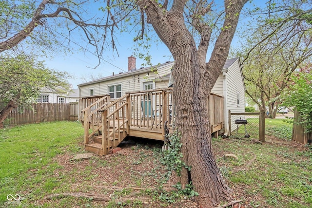 rear view of house with a lawn, a chimney, fence, and a wooden deck