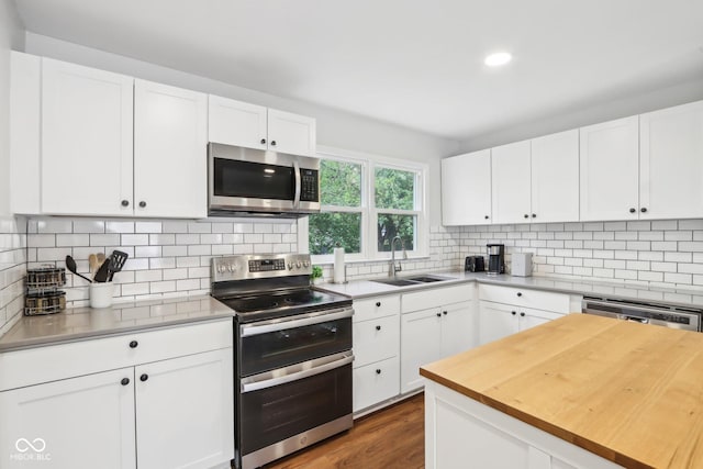 kitchen with backsplash, stainless steel appliances, butcher block counters, and a sink