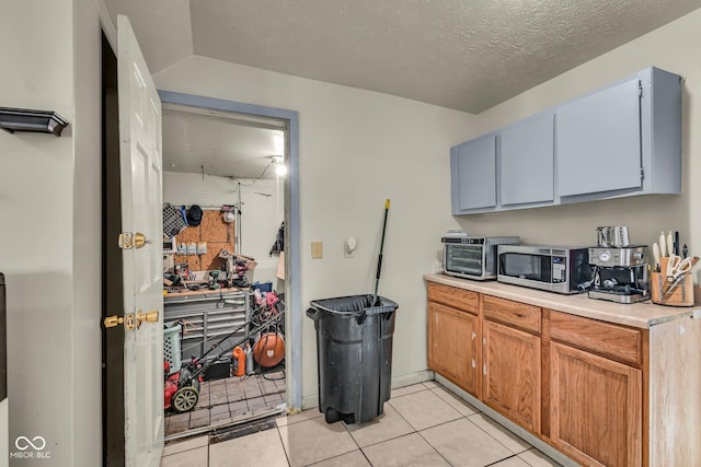 kitchen featuring stainless steel microwave, light countertops, and light tile patterned floors
