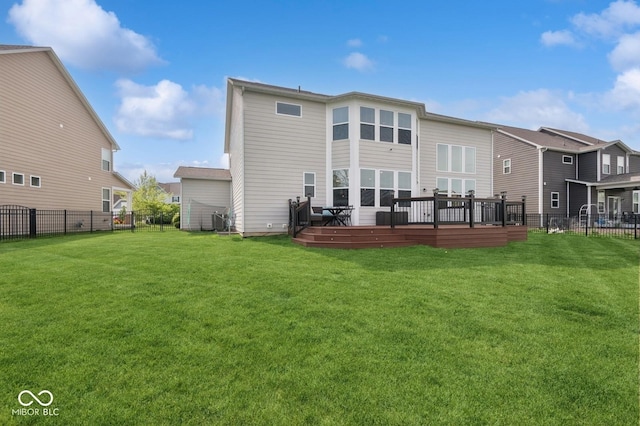 back of house featuring a wooden deck, fence, a lawn, and a residential view