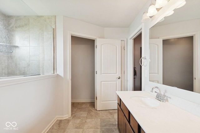 bathroom featuring vanity, baseboards, and a tile shower
