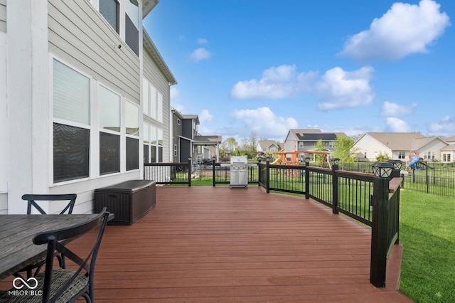 deck featuring a fenced backyard, a lawn, grilling area, and a residential view