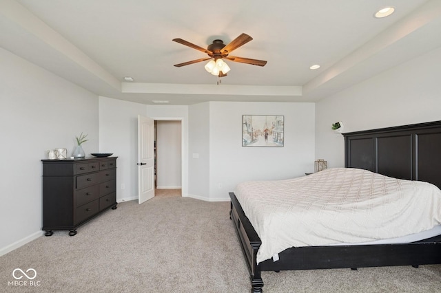 bedroom with a tray ceiling, light colored carpet, baseboards, and recessed lighting