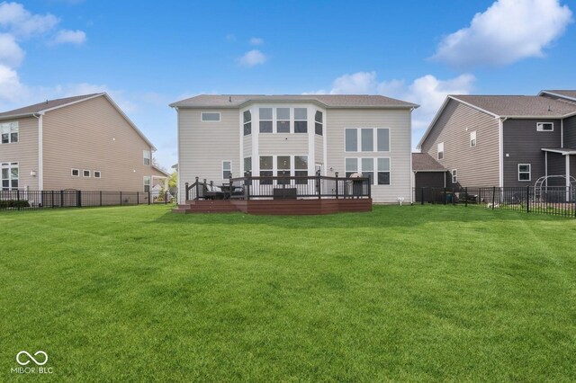 rear view of property with a lawn, a deck, and a fenced backyard