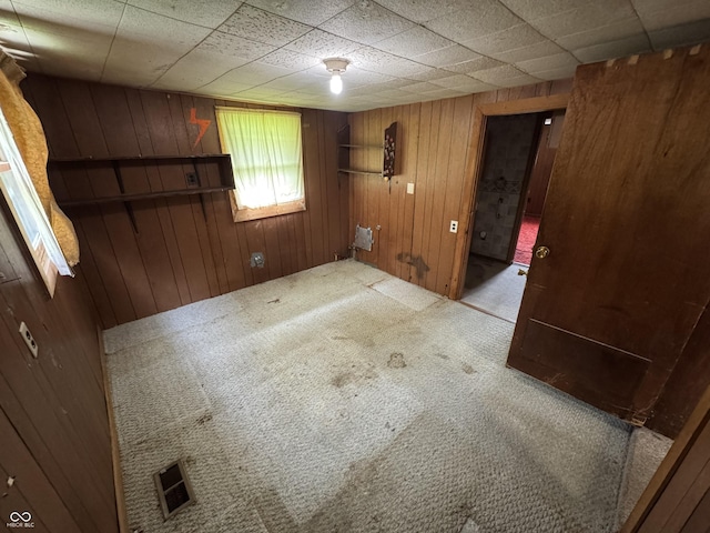 empty room with carpet and wooden walls