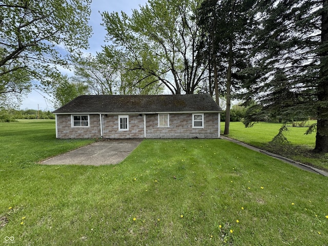 rear view of house featuring stone siding, a yard, and a patio area