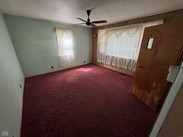carpeted spare room with visible vents and ceiling fan
