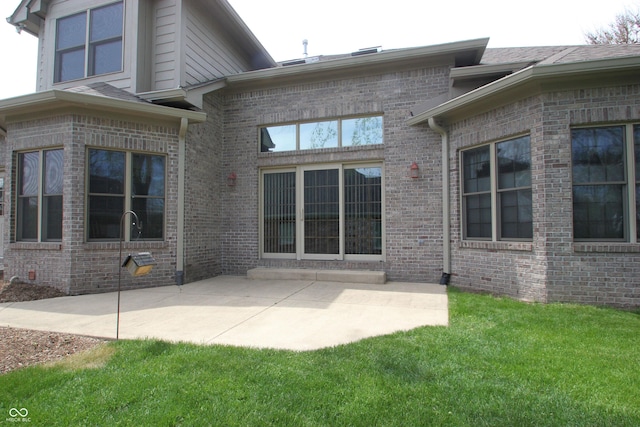 back of property featuring a patio area, brick siding, and a lawn