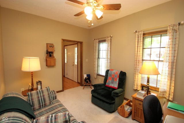 living area with ceiling fan, light colored carpet, and a healthy amount of sunlight