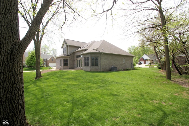 back of property featuring central air condition unit, a yard, and brick siding