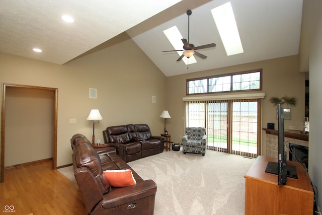 living area featuring a skylight, high vaulted ceiling, recessed lighting, ceiling fan, and baseboards