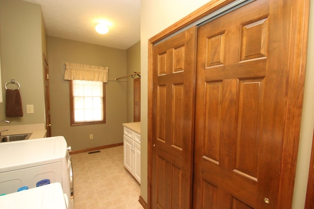 washroom with baseboards, visible vents, a sink, separate washer and dryer, and cabinet space